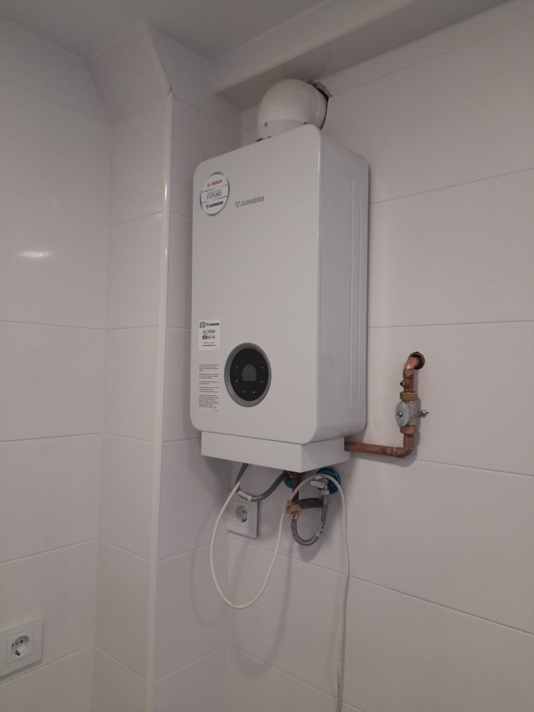 Calentador de agua de gas blanco montado en una pared.